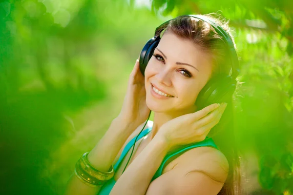 年轻漂亮的女人听听音乐，戴着耳机户外 — 图库照片