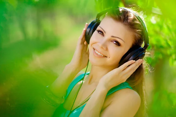 Beautiful young woman listen to music wearing headphones outdoor — Stock Photo, Image