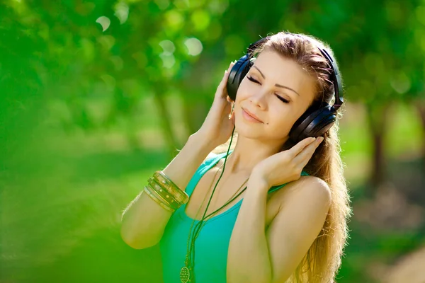 Beautiful young woman listen to music wearing headphones outdoor — Stock Photo, Image