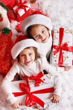 Noel hediyeleri gülümseyerek mutlu ve heyecanlı holding santa şapka Noel kız portresi. şirin mükemmel Noel Baba çocuğun kırmızı zemin üzerine.