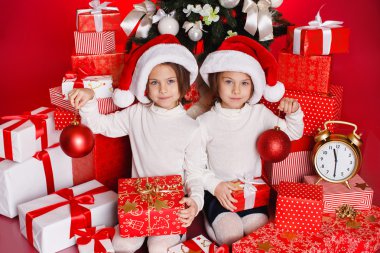 Noel hediyeleri gülümseyerek mutlu ve heyecanlı holding santa şapka Noel kız portresi. şirin mükemmel Noel Baba çocuğun kırmızı zemin üzerine.