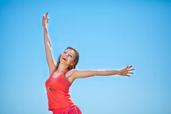 Portrait of a beautiful young woman in a red dress on a background of sky and grass in summer — Stock Photo, Image