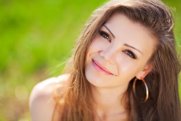 Porträt einer schönen jungen Frau in einem roten Kleid vor einem Hintergrund aus Himmel und Gras im Sommer — Stockfoto