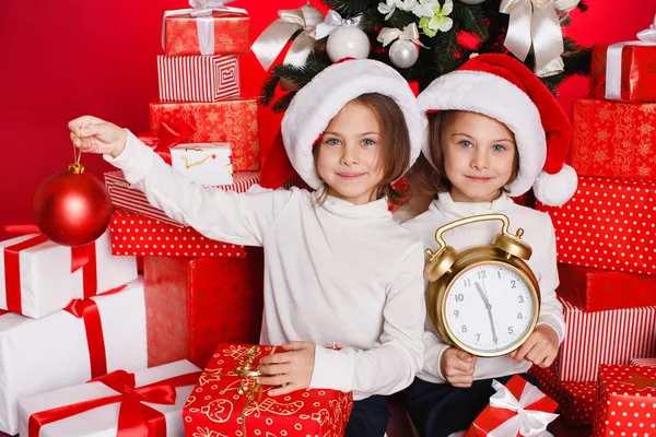 Porträt von Weihnachtsmädchen mit Weihnachtsgeschenken, die glücklich und aufgeregt lächeln. niedlich schön Weihnachtsmann Kinder auf rotem Hintergrund. — Stockfoto