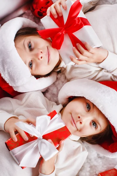 Portré santa kalap karácsonyi lányok tartja karácsonyi ajándékok mosolyog, boldog és izgatott. aranyos szép santa gyerekek piros háttér. — Stock Fotó