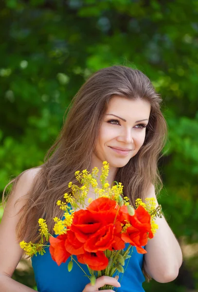 Porträtt av glad kvinna utomhus med röd vallmo blommor i händerna — Stockfoto