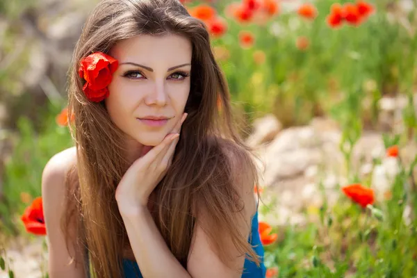 Portrait of cheerful woman outdoor with red poppy flowers in her hands — Stock Photo, Image