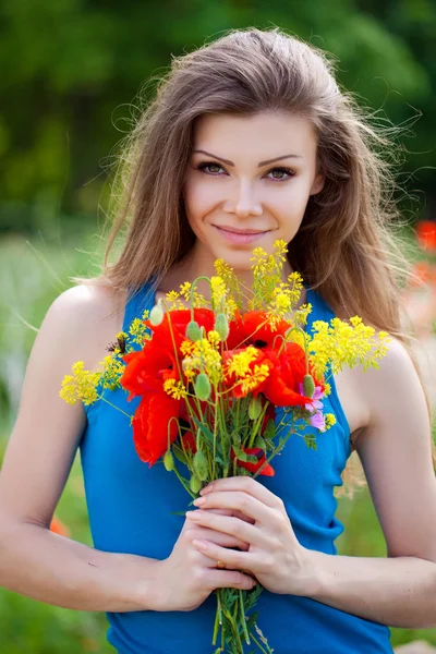 Porträt einer fröhlichen Frau im Freien mit roten Mohnblumen in ihren Händen — Stockfoto