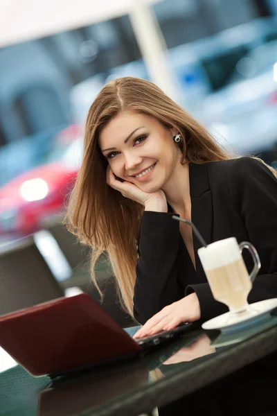 Retrato de una hermosa mujer sonriente sentada en un café con computadora portátil al aire libre — Foto de Stock