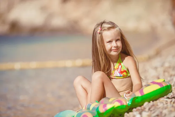 Little girl sitting on the beach near the sea — Stock Photo, Image