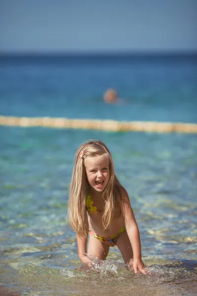 Bambina seduta sulla spiaggia vicino al mare — Foto Stock