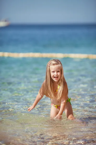 Liten flicka sitter på stranden nära havet — Stockfoto