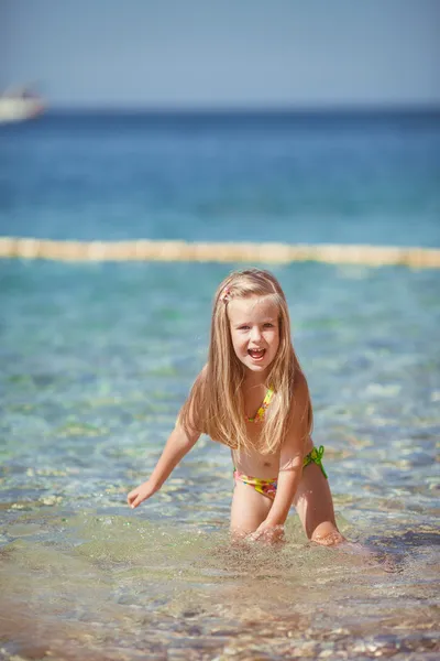 Bambina seduta sulla spiaggia vicino al mare — Foto Stock