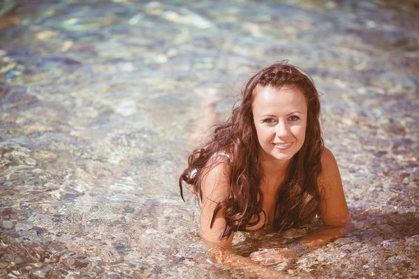 Mujer joven con el pelo mojado que yace cerca del mar —  Fotos de Stock