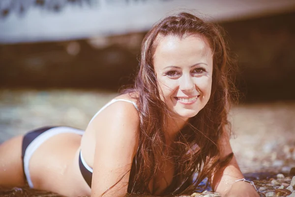 Mladá žena s mokrými vlasy, ležící u moře — Stock fotografie