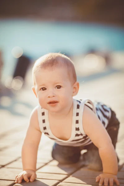 海のそばで屋外で遊ぶ幸せの小さな男の子の肖像画のドックします。 — ストック写真