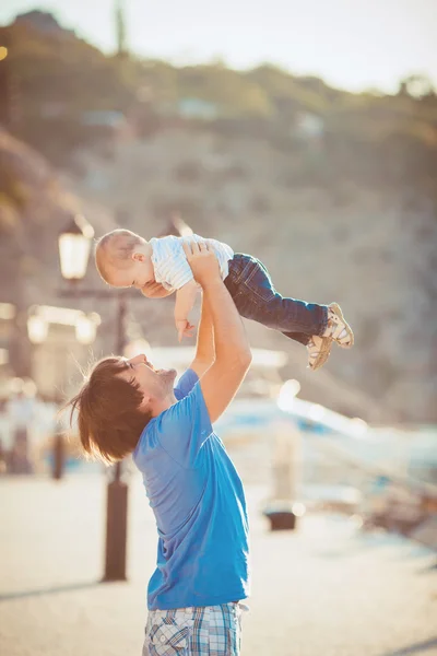 Der Vater spielt mit seinem Sohn im Sommer auf der Seebrücke in der Nähe des Yachtclubs. Außenbereich — Stockfoto