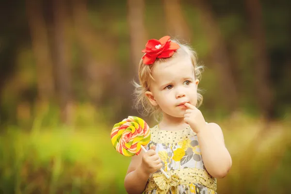 Gelukkig meisje likt zoete suikergoed aard zomer buiten — Stockfoto