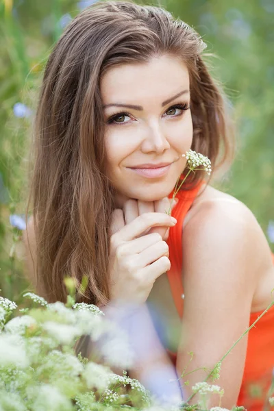 Beautiful young brunette woman on the meadow with white flowers on a warm summer day — Stock Photo, Image