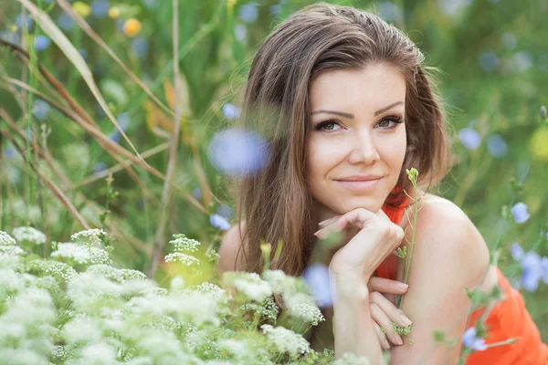 Beautiful young brunette woman on the meadow with white flowers on a warm summer day — Stock Photo, Image