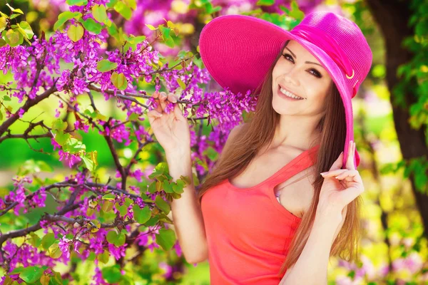 Schöne junge brünette Frau auf der Wiese mit weißen Blumen an einem warmen Sommertag — Stockfoto