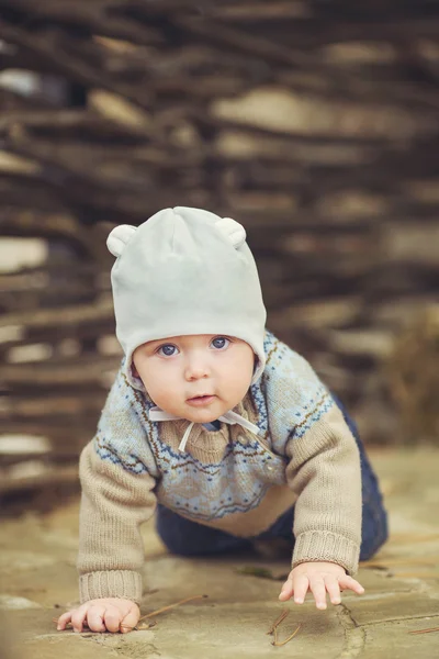 Kleiner süßer Junge, der im Herbst draußen sitzt. Kürbisse liegen herum — Stockfoto