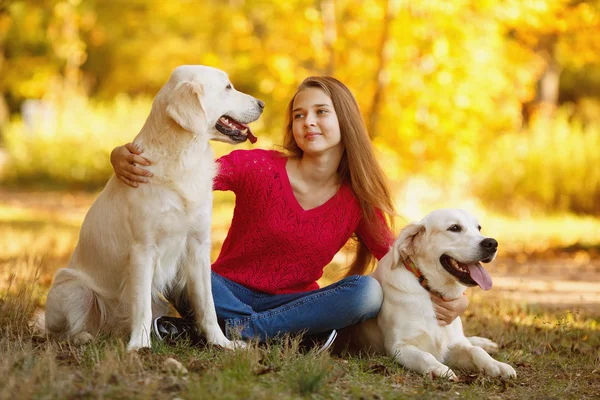 Retrato de la joven sentada en el suelo con su perro recuperador en la escena de otoño — Foto de Stock