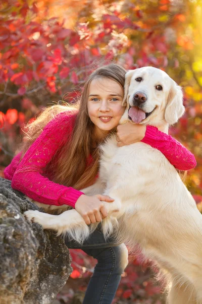 Retrato de la joven sentada en el suelo con su perro recuperador en la escena de otoño —  Fotos de Stock