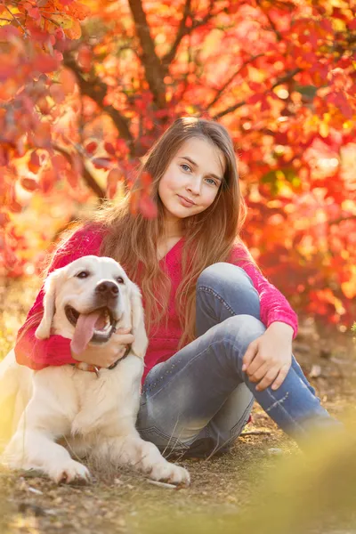 Porträtt av ung flicka sitter på marken med hennes hund retriever i höst scen — Stockfoto