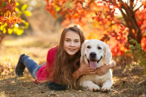 Retrato de la joven sentada en el suelo con su perro recuperador en la escena de otoño —  Fotos de Stock