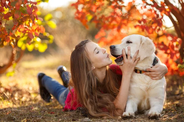 Portret van een jong meisje, zittend op de grond met haar hond retriever in herfst scène — Stockfoto