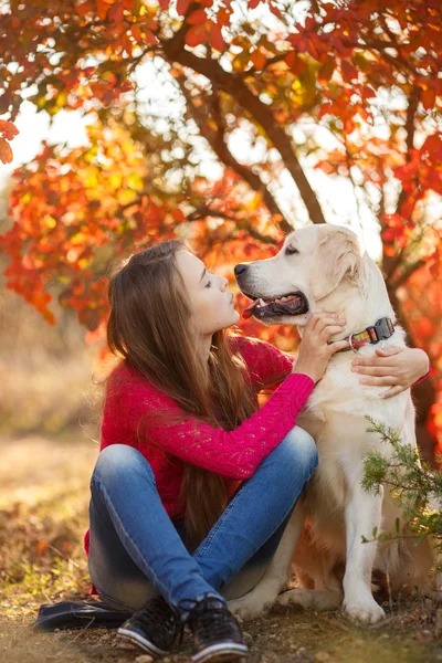 Retrato de la joven sentada en el suelo con su perro recuperador en la escena de otoño — Foto de Stock