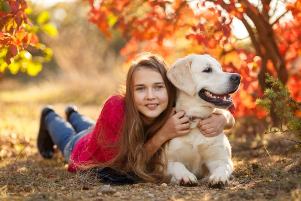 Porträt eines jungen Mädchens, das mit ihrem Hund Retriever in der Herbstszene auf dem Boden sitzt — Stockfoto