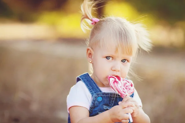 Little girl with big sweet walks in park — Stock Photo, Image