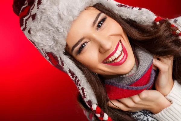 Портрет девушки в зимней одежде с ярким макияжем на красном фоне — стоковое фото