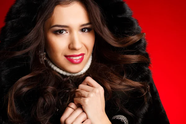 Portrait of girl in winter clothes with bright make-up on a red background — Stock Photo, Image