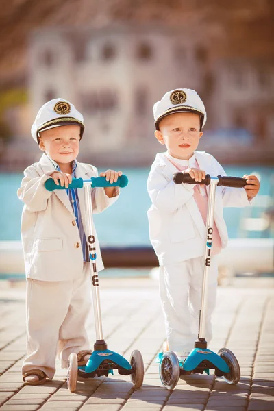 Two little boys riding on scooter bicycle in summer — Stock Photo, Image