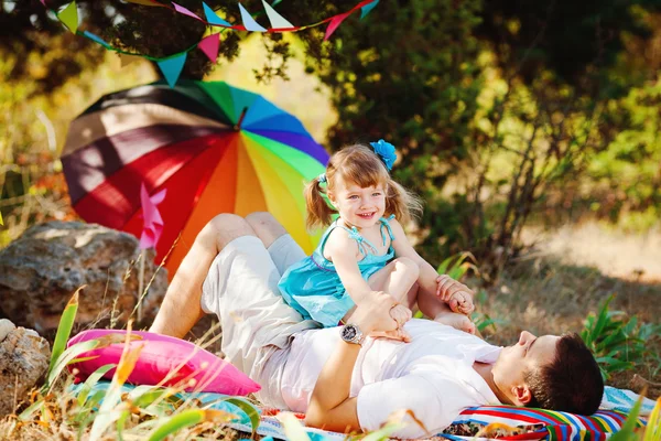 Счастливая молодая семья с ребенком отдыхает на свежем воздухе в летнем парке — стоковое фото