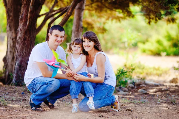 Gelukkig jonge gezin met kind buiten rusten in zomer park — Stockfoto