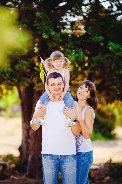 Feliz familia joven con el niño descansando al aire libre en el parque de verano — Foto de Stock