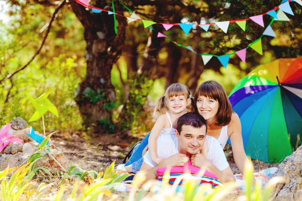 Gelukkig jonge gezin met kind buiten rusten in zomer park — Stockfoto