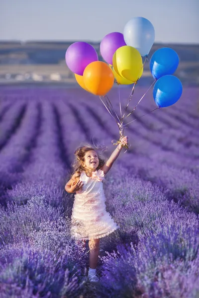 Leende flicka sniffning blommor i ett lavendel fält — Stockfoto