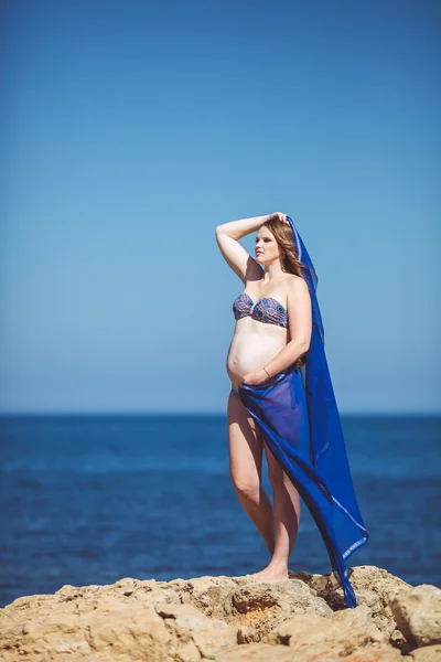 Mladá těhotná žena dýchá čerstvý mořský vzduch na pozadí hory — Stock fotografie
