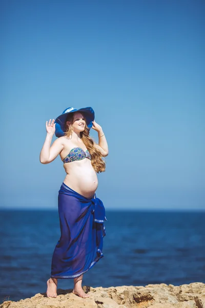 Mladá těhotná žena dýchá čerstvý mořský vzduch na pozadí hory — Stock fotografie