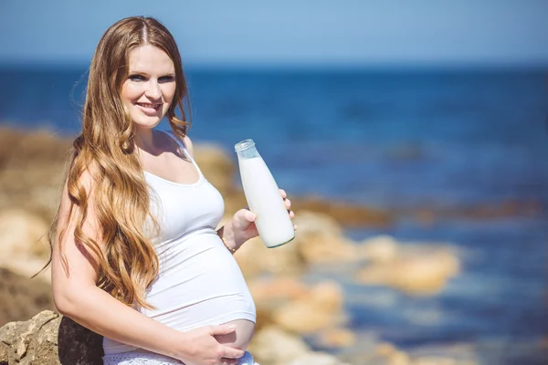 Young pregnant woman breathes the fresh sea air on a background of mountains — Stock Photo, Image