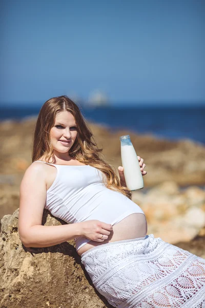 Молодая беременная женщина дышит свежим морским воздухом на фоне гор — стоковое фото
