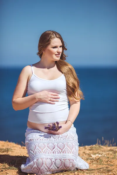 Junge schwangere Frau atmet die frische Meeresluft vor dem Hintergrund der Berge — Stockfoto