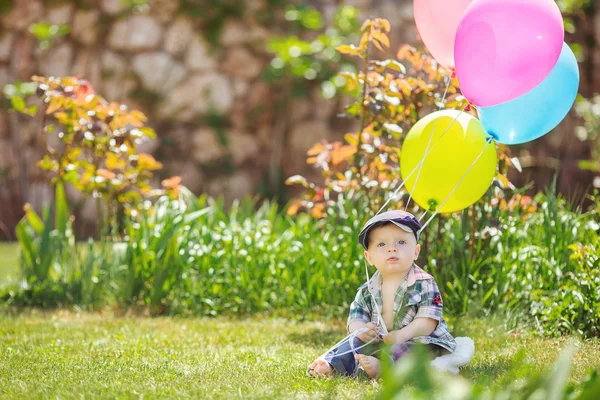 Portret uroczy mały chłopiec siedzi na trawie — Zdjęcie stockowe