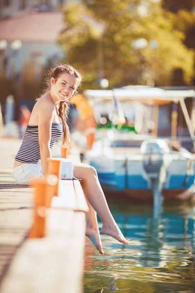Young woman lengthened on a quay at the edge of a lake — Stock Photo, Image