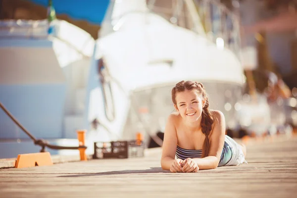 Mujer joven alargada en un muelle en el borde de un lago — Foto de Stock